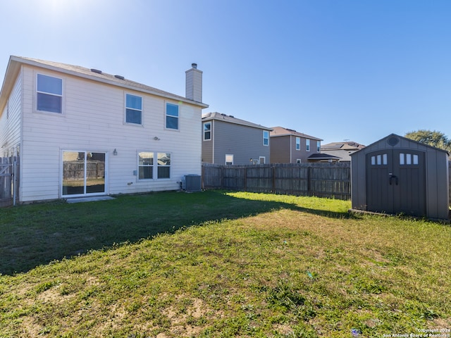 back of house featuring central air condition unit, a yard, and a storage shed