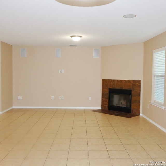 unfurnished living room with a tiled fireplace and light tile patterned floors