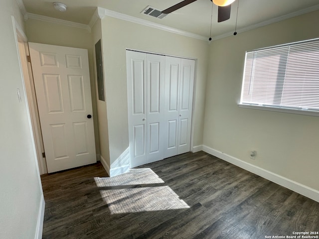 unfurnished bedroom with ceiling fan, a closet, dark wood-type flooring, and ornamental molding