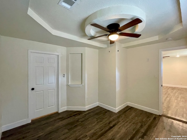 spare room with a raised ceiling, ceiling fan, dark hardwood / wood-style flooring, and a textured ceiling