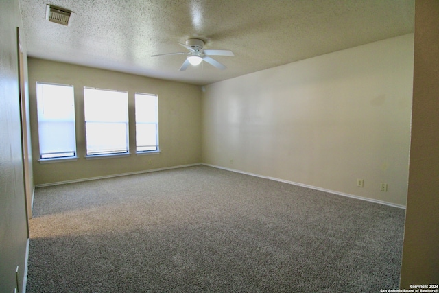 spare room featuring ceiling fan, carpet, and a textured ceiling