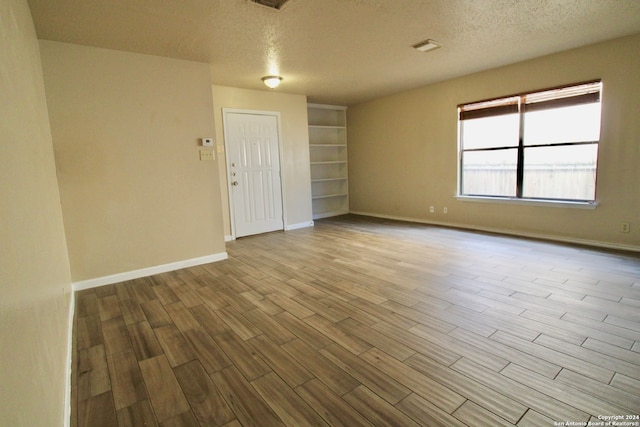 unfurnished room featuring a textured ceiling and light wood-type flooring