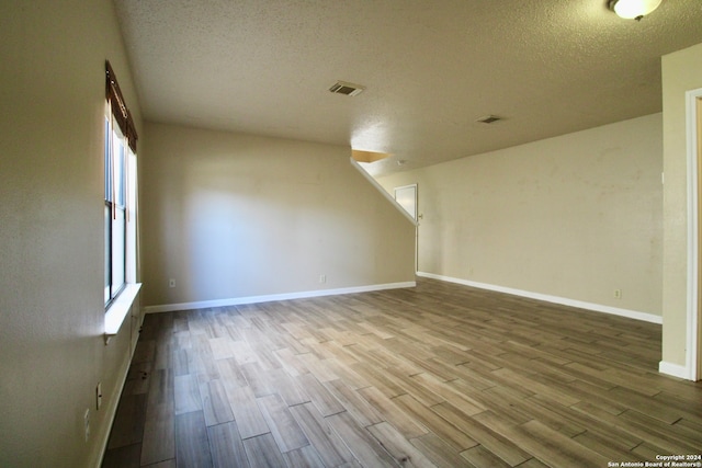 unfurnished room featuring a textured ceiling, light hardwood / wood-style flooring, and plenty of natural light