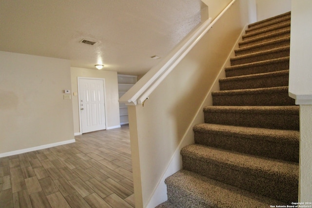 staircase featuring a textured ceiling and hardwood / wood-style flooring