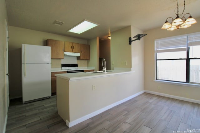 kitchen featuring white appliances, sink, decorative light fixtures, light hardwood / wood-style floors, and kitchen peninsula