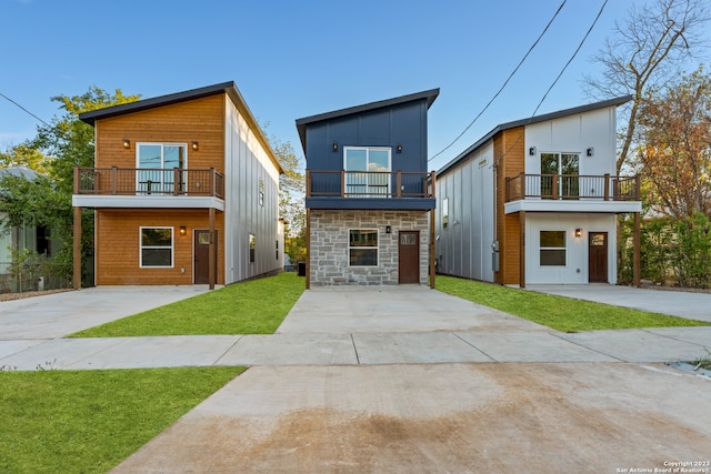 contemporary house featuring a balcony and a front lawn