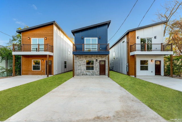 contemporary house featuring a garage, a balcony, and a front yard