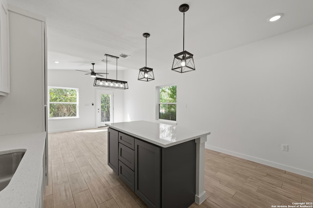 kitchen featuring ceiling fan, a kitchen island, light hardwood / wood-style floors, and hanging light fixtures