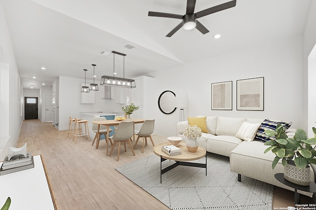 living room featuring ceiling fan with notable chandelier and light wood-type flooring