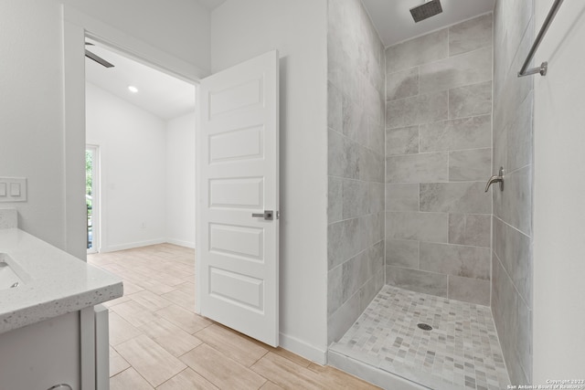 bathroom with vanity, ceiling fan, lofted ceiling, and tiled shower