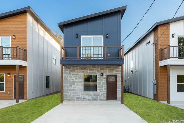 rear view of property featuring a yard and a balcony