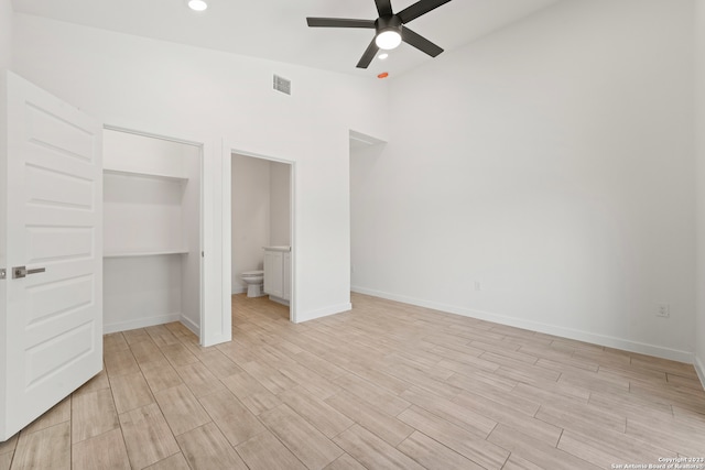 unfurnished bedroom featuring ensuite bath, ceiling fan, a closet, and light wood-type flooring