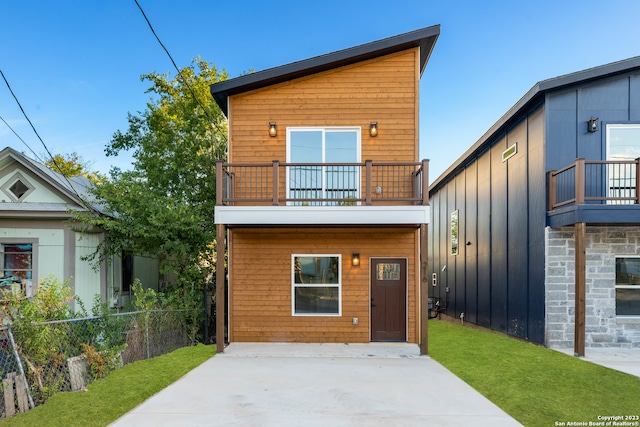 rear view of house featuring a lawn and a balcony