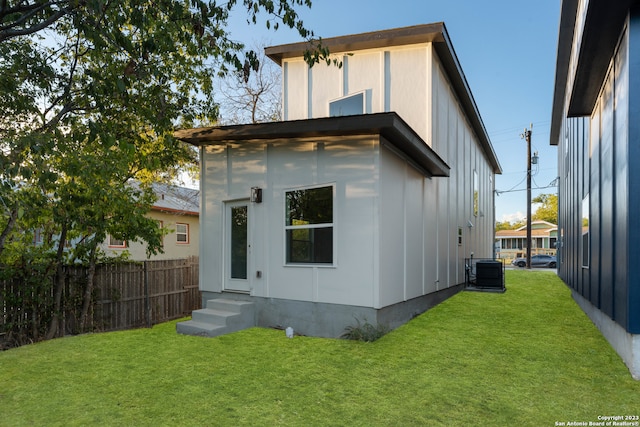 back of property featuring central AC and a yard