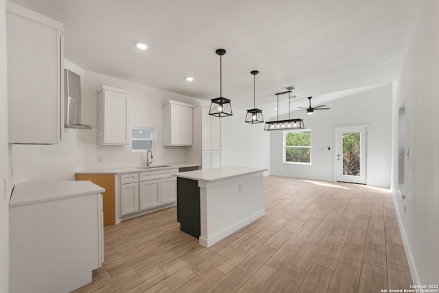 kitchen with light hardwood / wood-style floors, a kitchen island, white cabinetry, and sink