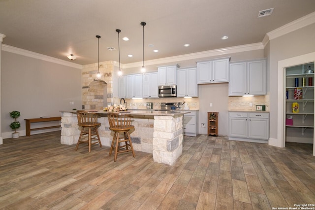 2407 Fm 1283, Pipe Creek, TX 78063 - kitchen with stainless steel appliances, ornamental molding, backsplash, a kitchen island with sink, and a kitchen breakfast bar