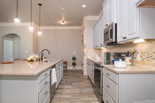 kitchen featuring white cabinets, sink, light stone countertops, decorative light fixtures, and stainless steel appliances