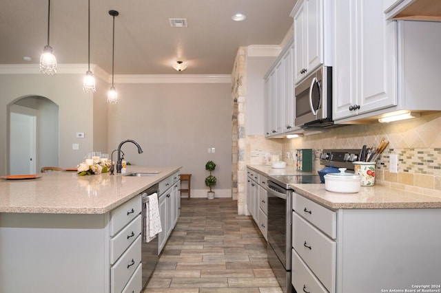 2407 Fm 1283, Pipe Creek, TX 78063 - kitchen featuring appliances with stainless steel finishes, a sink, arched walkways, ornamental molding, and white cabinets