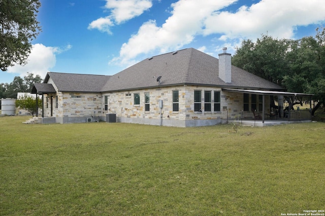2407 Fm 1283, Pipe Creek, TX 78063 - back of house with stone siding, a chimney, a lawn, a patio area, and central AC unit