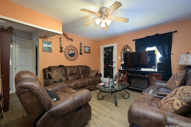 living room with ceiling fan, a fireplace, and light wood-type flooring