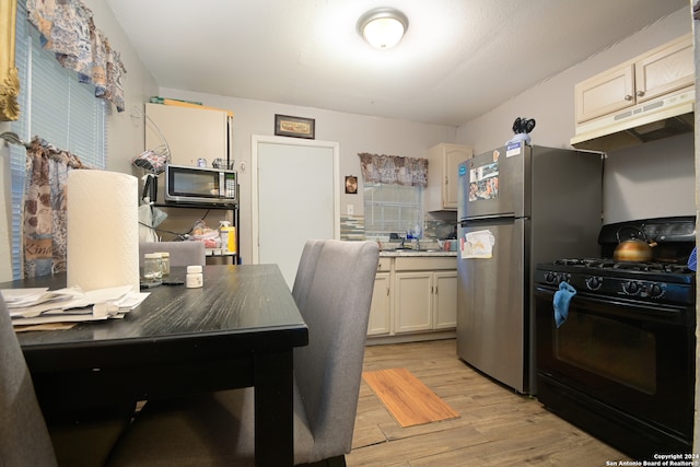 kitchen featuring black gas stove, light wood-type flooring, and sink