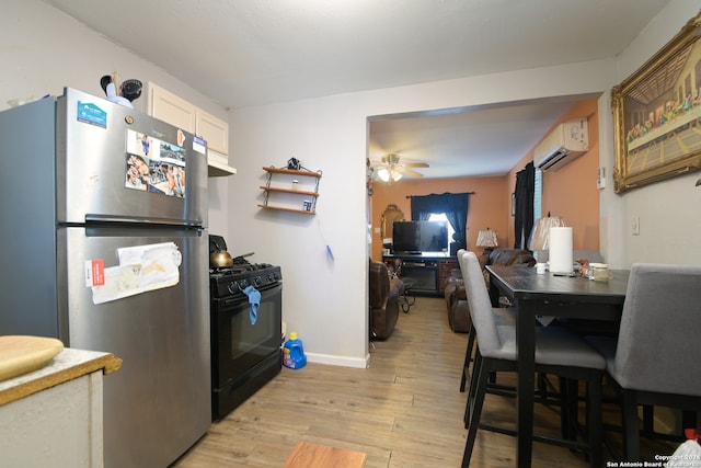 kitchen featuring white cabinetry, a wall mounted air conditioner, light hardwood / wood-style flooring, stainless steel fridge, and black range with gas cooktop