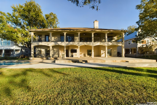 rear view of property with a yard, a balcony, and a patio