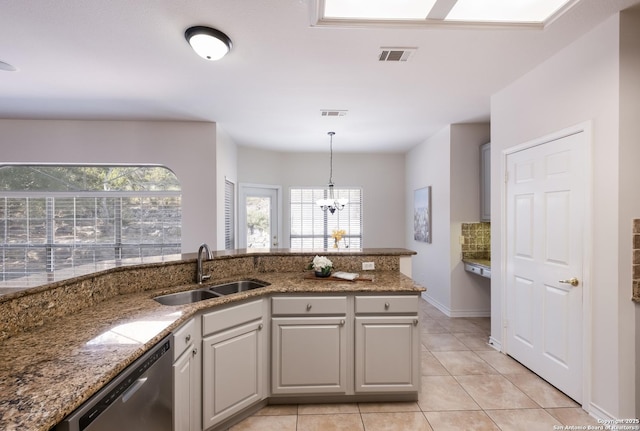 kitchen featuring stainless steel dishwasher, a sink, a chandelier, light tile patterned floors, and plenty of natural light
