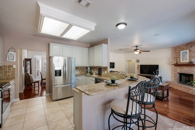 kitchen featuring a kitchen breakfast bar, kitchen peninsula, light hardwood / wood-style flooring, and appliances with stainless steel finishes