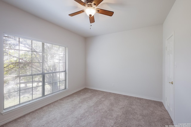 carpeted spare room featuring a ceiling fan and baseboards