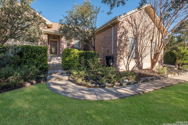 obstructed view of property with a front yard and brick siding