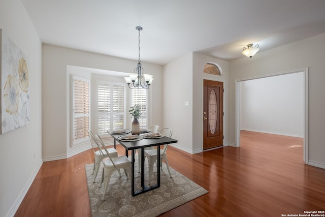 dining area with a chandelier, wood finished floors, and baseboards