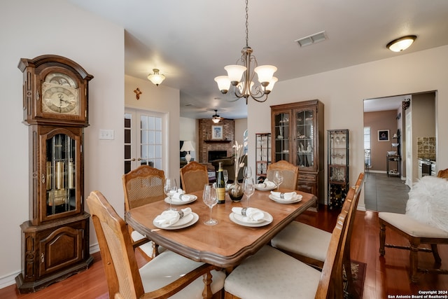 dining area featuring hardwood / wood-style floors, ceiling fan with notable chandelier, and a fireplace