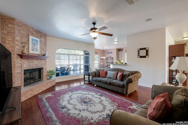 living room featuring a fireplace, dark wood-type flooring, and ceiling fan with notable chandelier