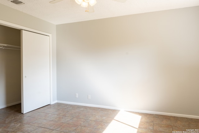 unfurnished bedroom featuring ceiling fan, a textured ceiling, and a closet