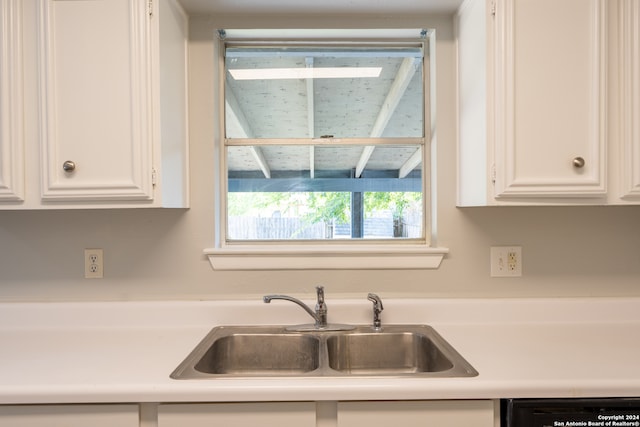 kitchen featuring white cabinets, black dishwasher, and sink