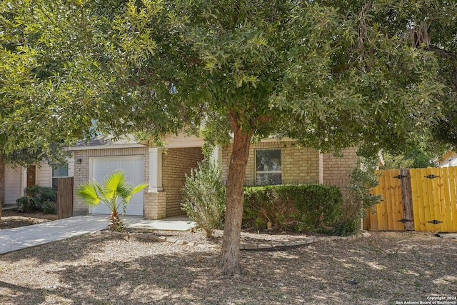 2115 Clear Ct, San Antonio, TX 78227 - view of property hidden behind natural elements featuring brick siding, fence, a garage, driveway, and a gate