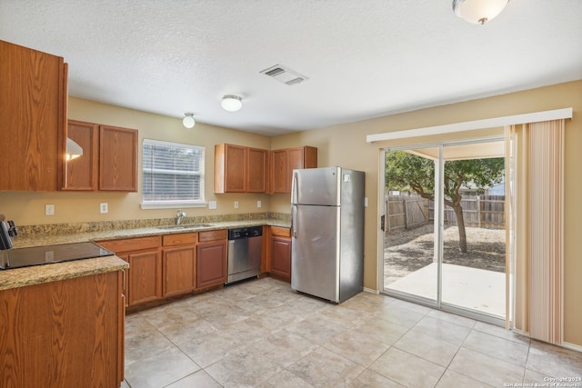 kitchen with sink, light tile patterned floors, stainless steel appliances, and a textured ceiling