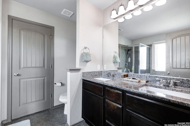 bathroom featuring tile patterned flooring, vanity, toilet, and a shower with shower door