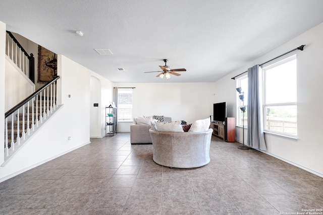 living room with ceiling fan, tile patterned flooring, and a textured ceiling