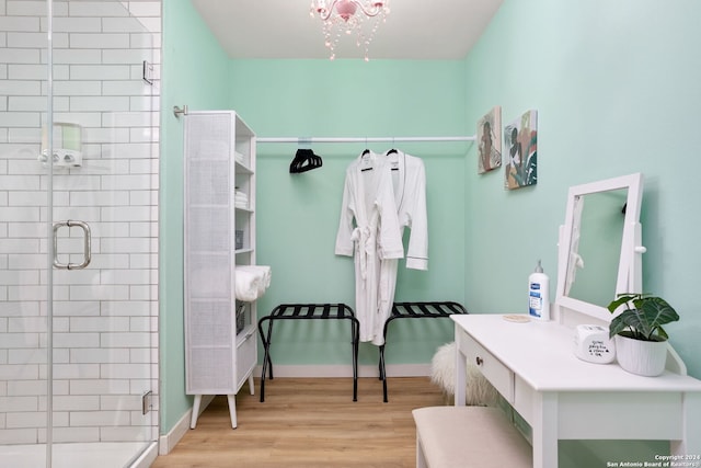 bathroom featuring a shower with shower door, hardwood / wood-style floors, and a notable chandelier