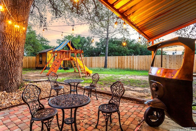 patio terrace at dusk featuring a playground