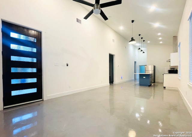 unfurnished living room with ceiling fan and a towering ceiling