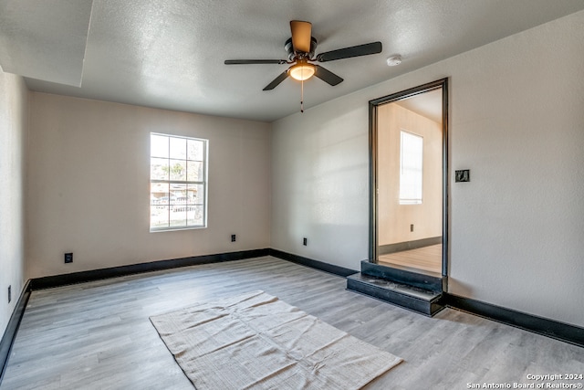 spare room featuring ceiling fan, a textured ceiling, and light wood-type flooring