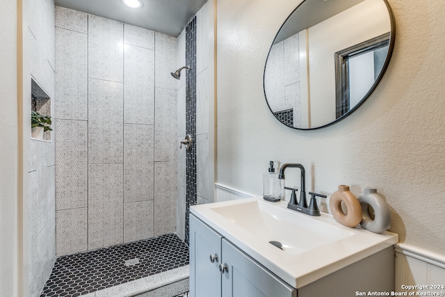 bathroom featuring tiled shower and vanity