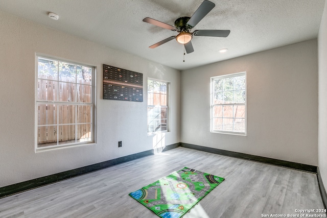 empty room featuring a textured ceiling, light hardwood / wood-style flooring, and ceiling fan