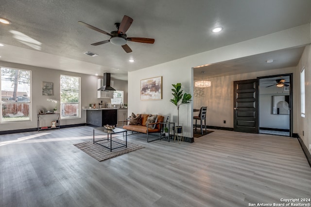 living room featuring hardwood / wood-style floors, ceiling fan with notable chandelier, a textured ceiling, and sink