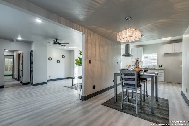 dining room with ceiling fan with notable chandelier and light hardwood / wood-style floors