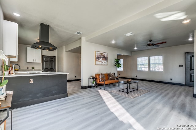 living room featuring ceiling fan, light wood-type flooring, and sink