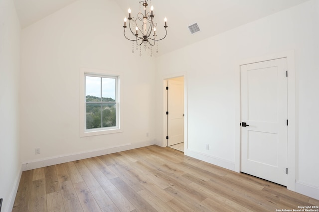 spare room featuring a chandelier, high vaulted ceiling, and light hardwood / wood-style flooring